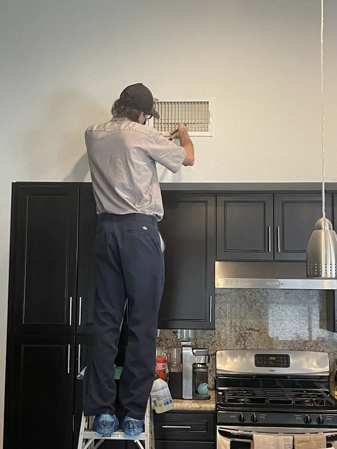 Technician inspecting an air vent during HVAC service in Garden City